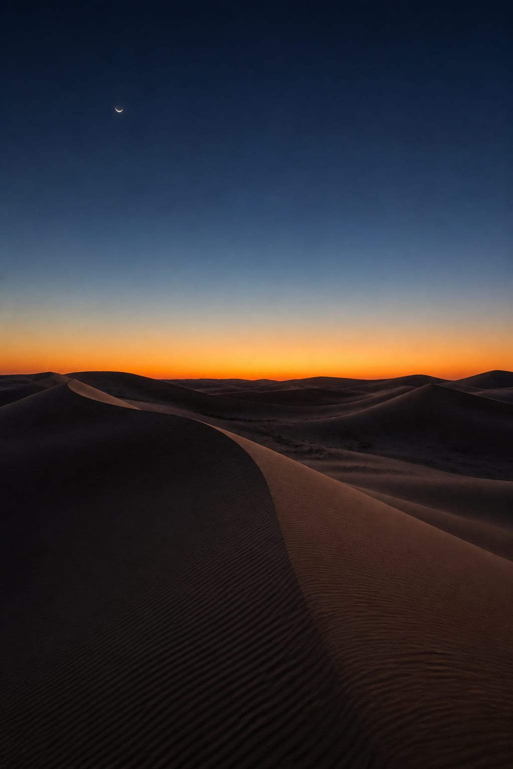 AI-generated desert dunes beneath a crescent moon at blue hour