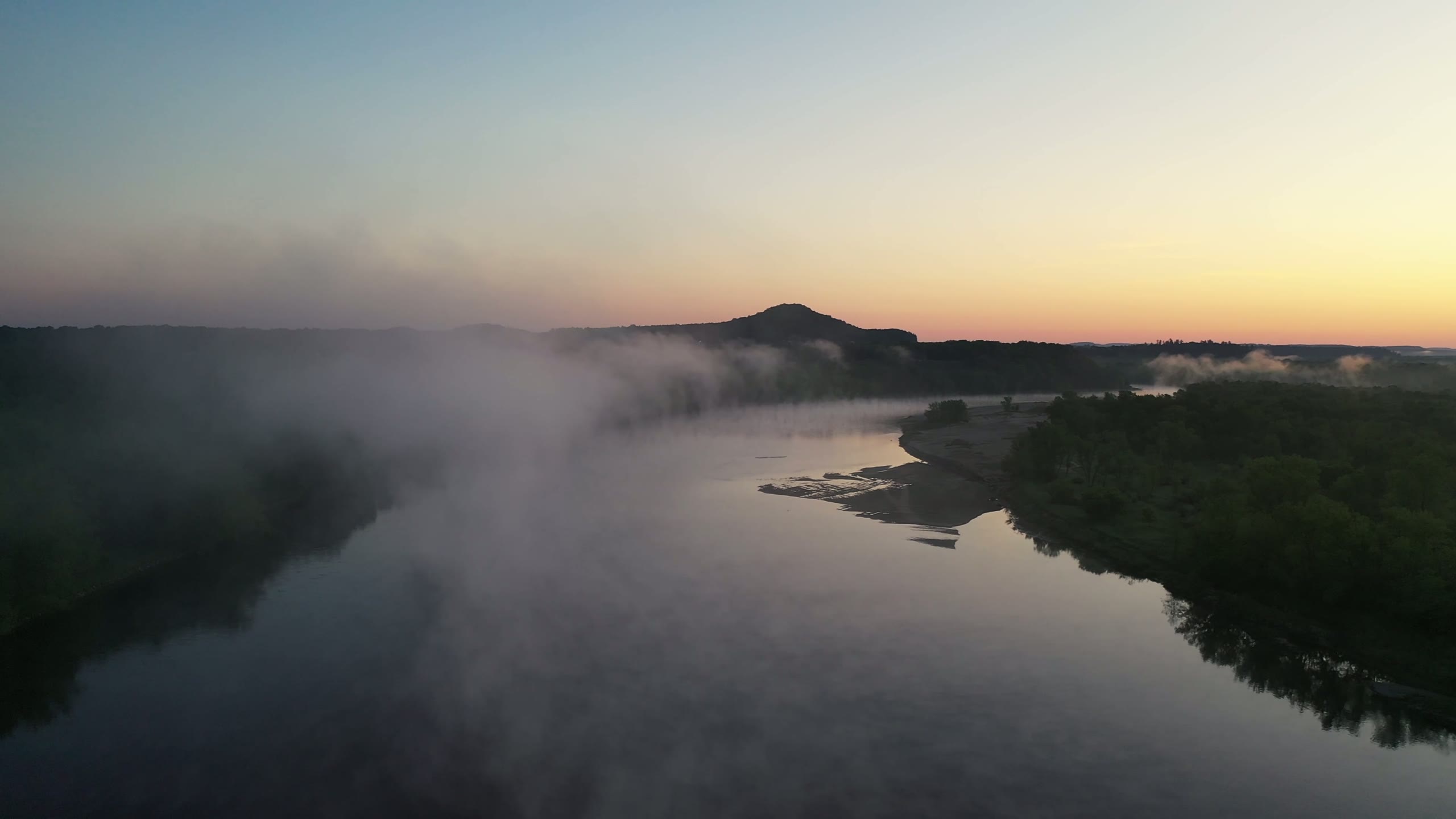 Mist over a river at dusk, then sun through pines across a still lake
